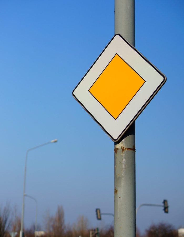A low angle shot of a priority traffic sign under a clear blue sky